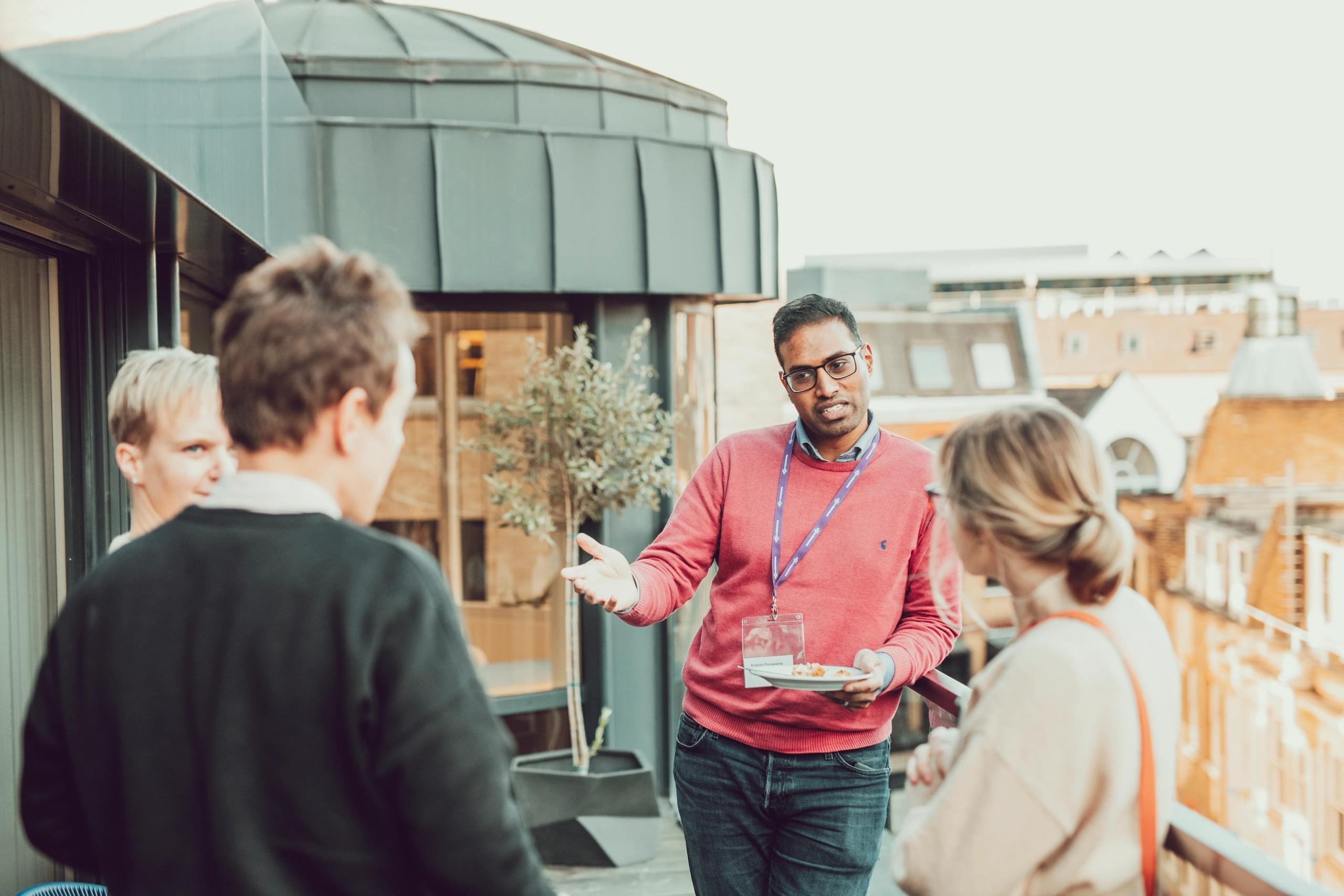 A group of people in conversation on a rooftop