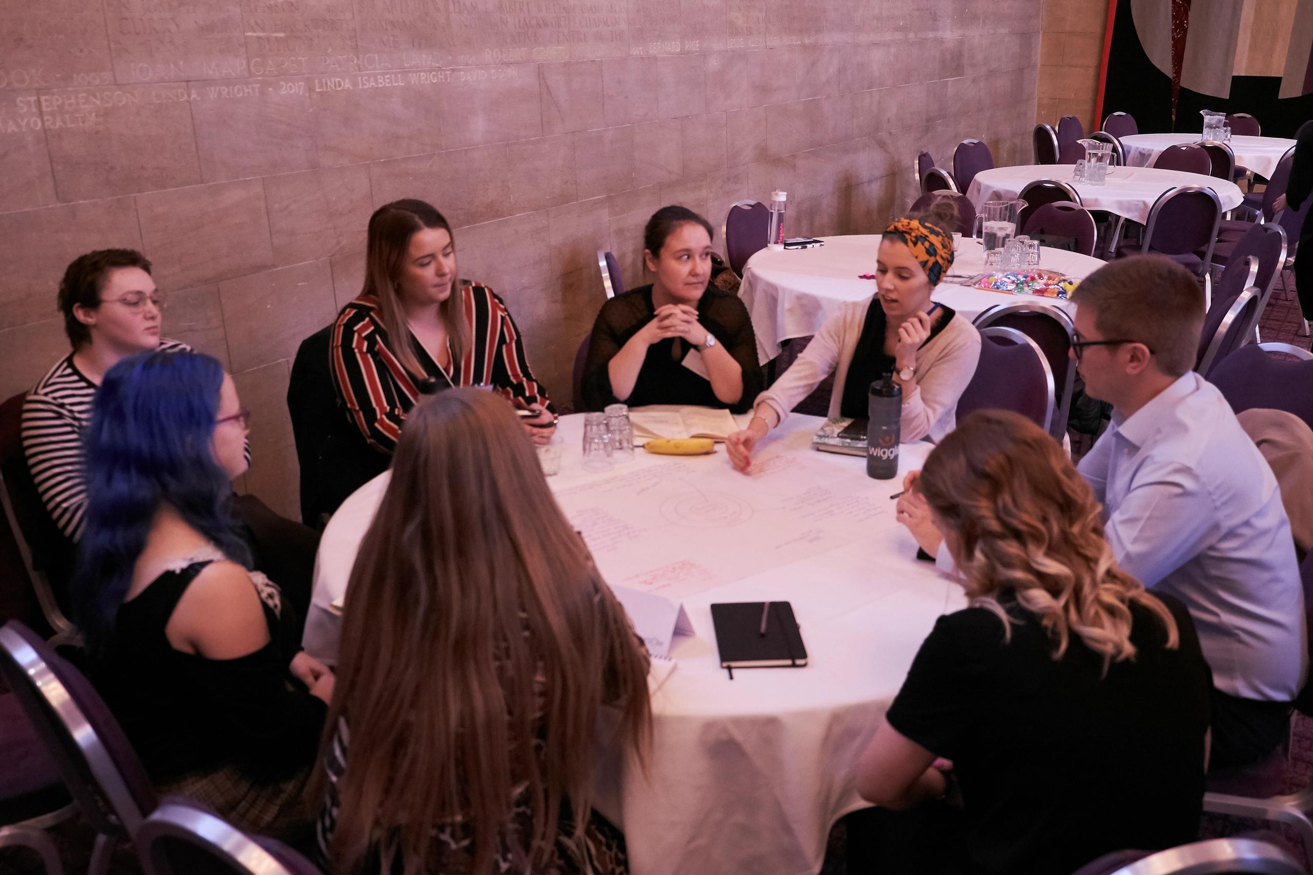 A group of young people in conversation around a table