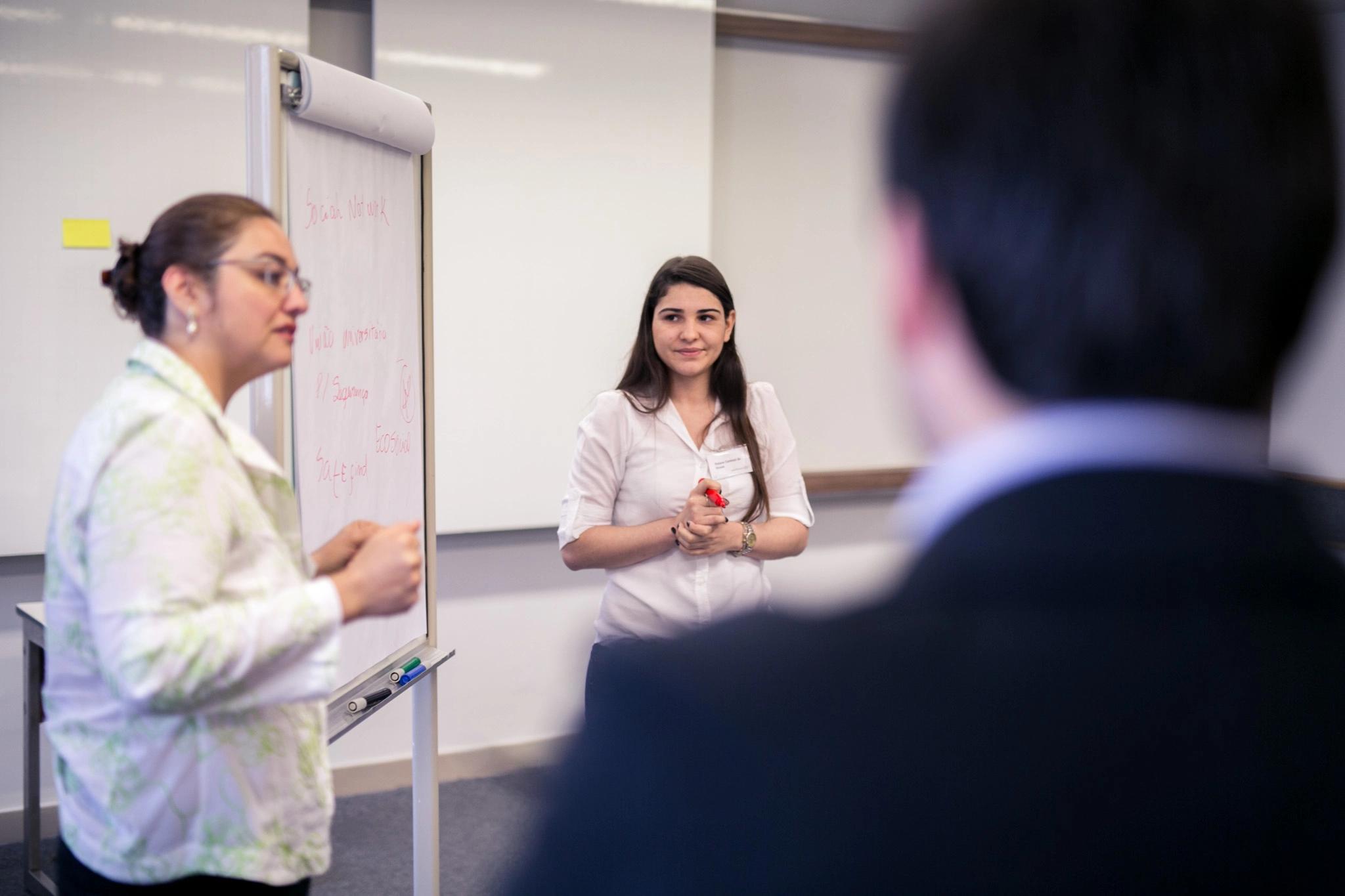 Two young women presenting in front of a flipchart