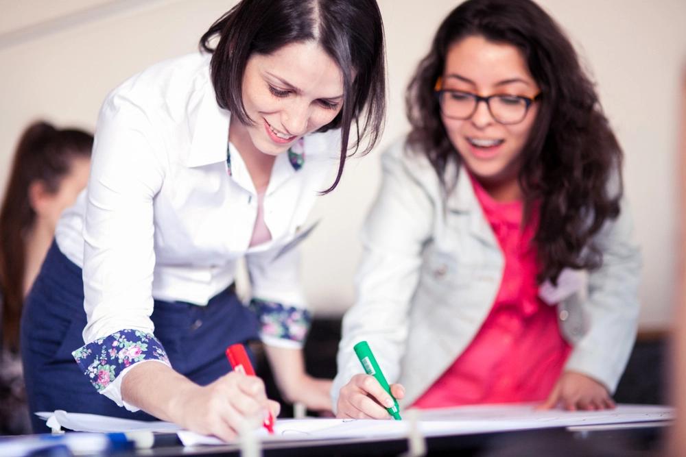 Two young women writing on a poster