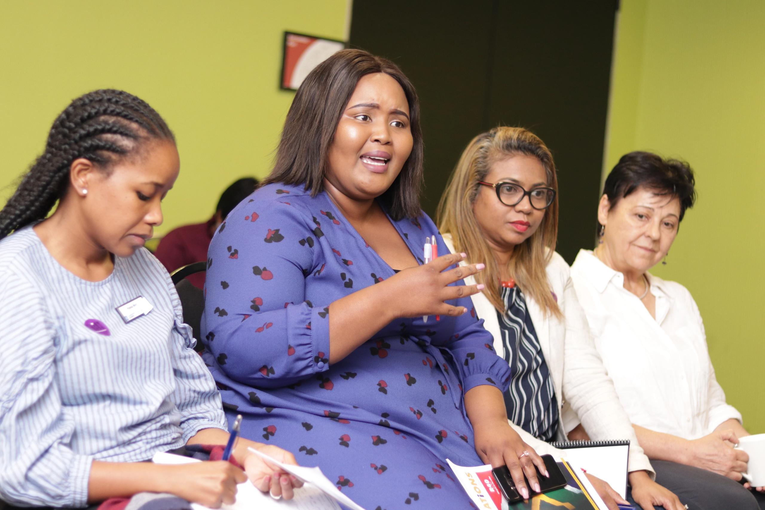 Woman speaking whilst seated among other women