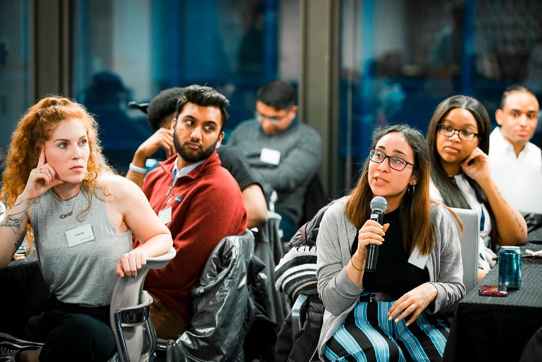 Young woman sitting at a table speaking into a microphone